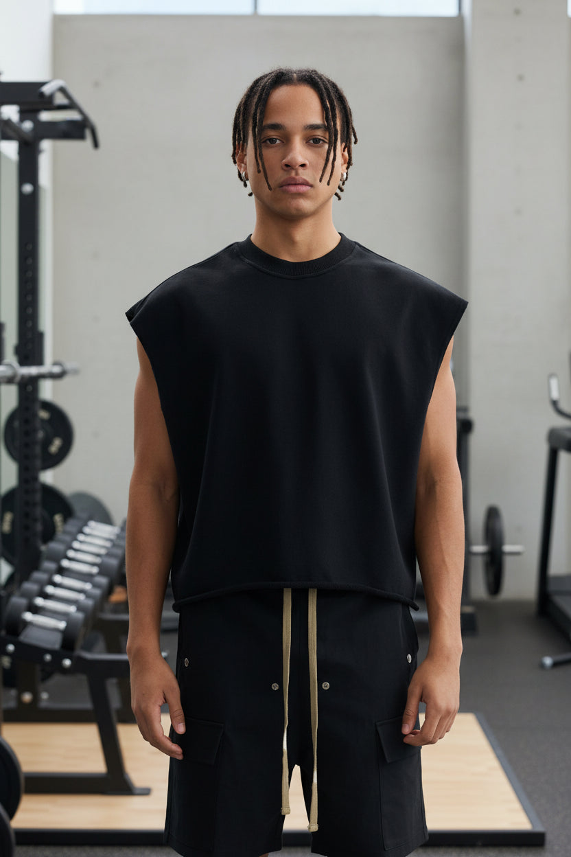 Person wearing a black sleeveless top and black pants on a white background