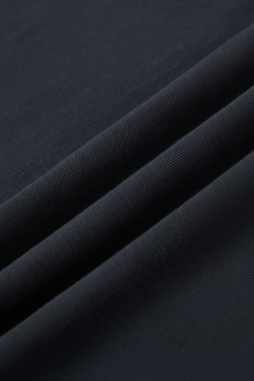 A close-up of dark navy blue fabric with soft diagonal folds showing the material texture.