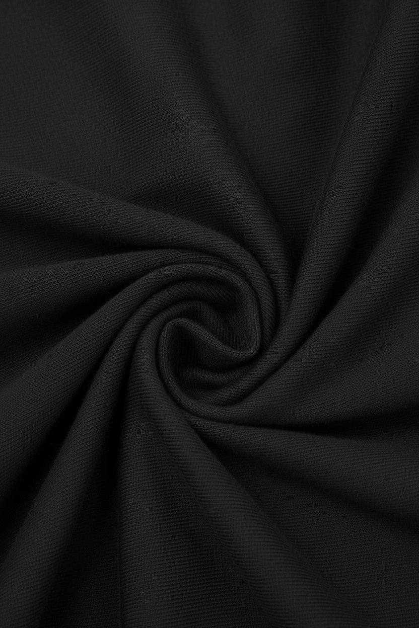 A close-up of black textured fabric arranged in a spiral drape, showing the material's fine ribbed weave and soft folds.