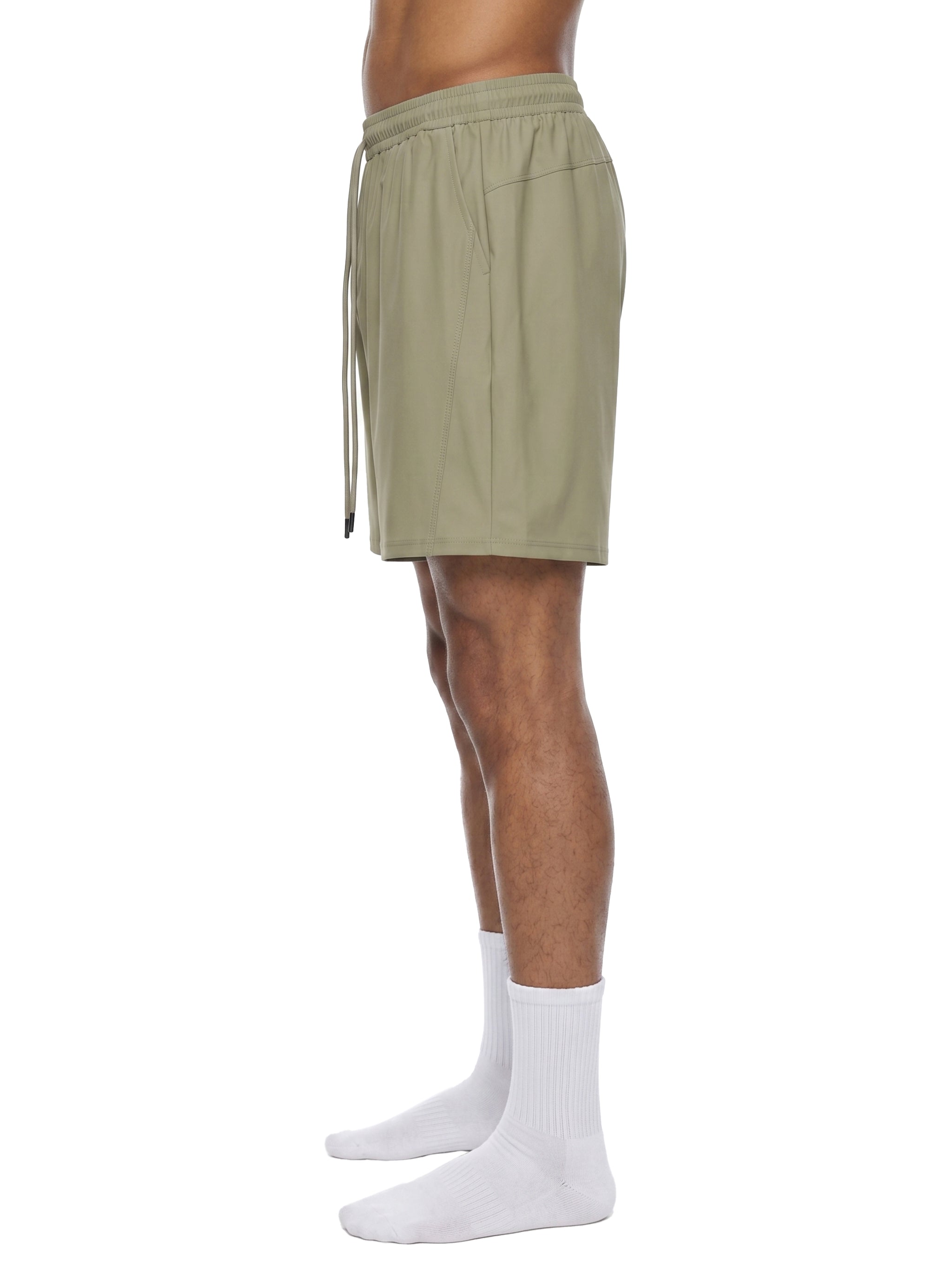 Person wearing olive green shorts and white socks on a white background