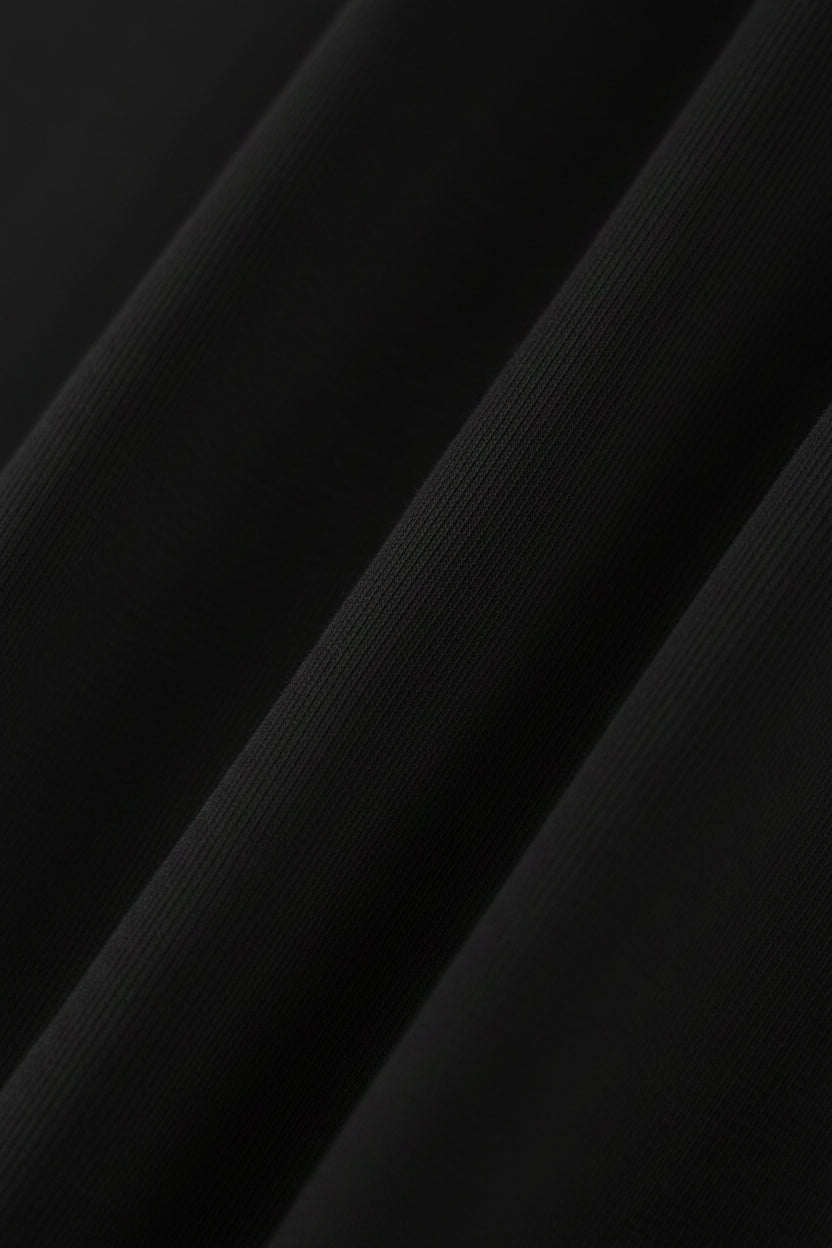 A close-up of black ribbed fabric with soft diagonal folds and a smooth texture.