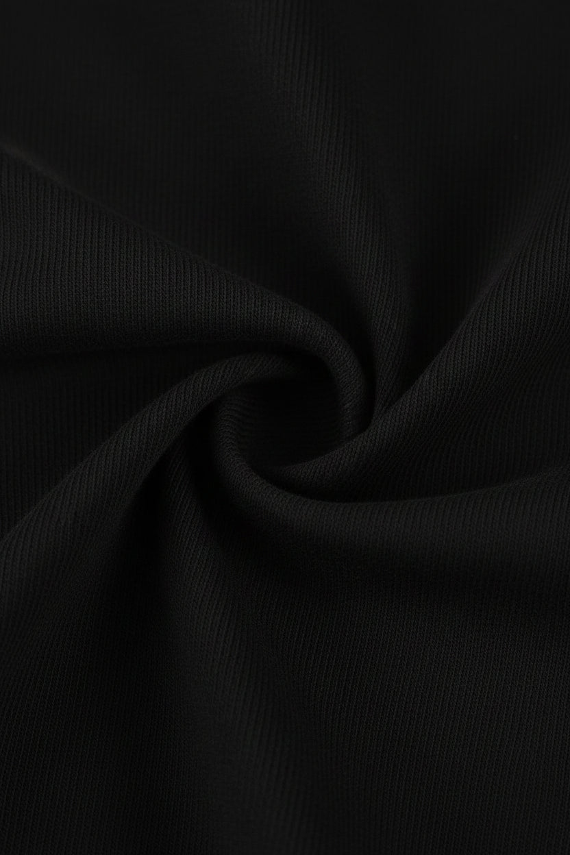 A close-up of black ribbed fabric with a central swirl, showing the material texture and color.